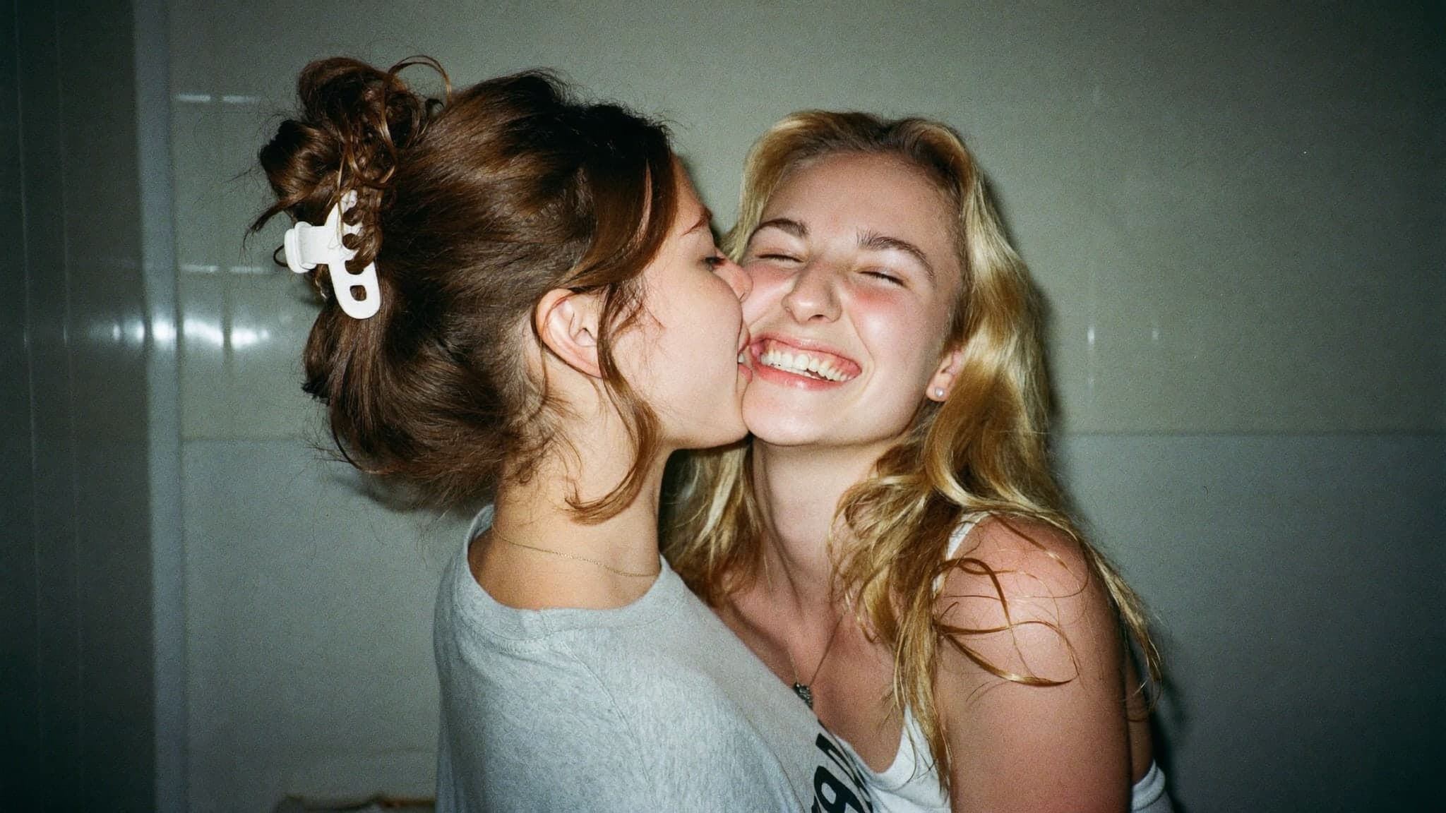 Two friends laughing as one kisses the other on the cheek
